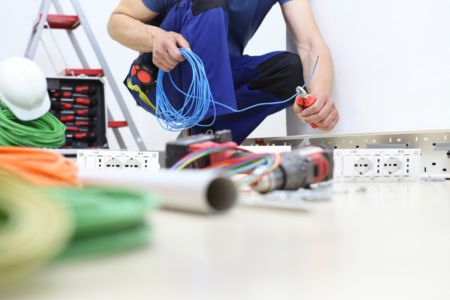 Electrician with wiring components on the floor.