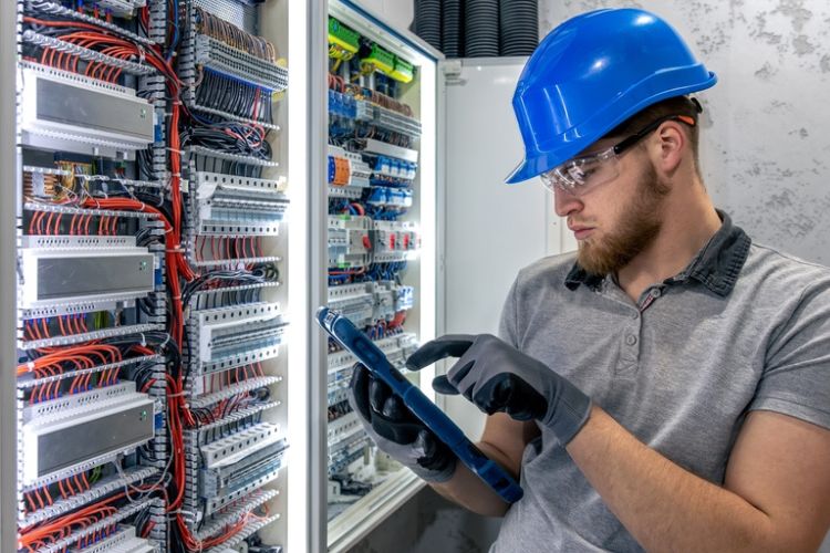 Professional electrician surveying a complex panel