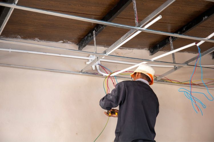 electrician installing electrical wiring through ceiling for home rewiring