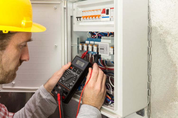 electrician testing electrical panel with multimeter during wiring service