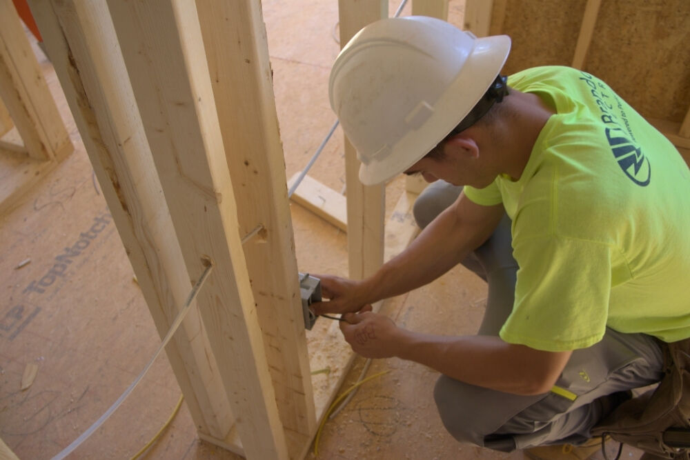 Electrician installing a power outlet in a new construction site